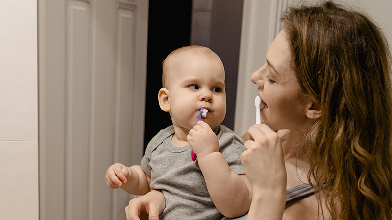 baby and mother brushing teeth